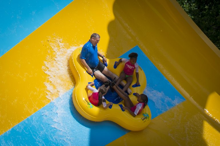 Park President Carl Lum and three fifth-graders from An Achievable Dream take one of the first trips down Colossal Curl. (WYDaily/Courtesy of SeaWorld Parks & Entertainment)