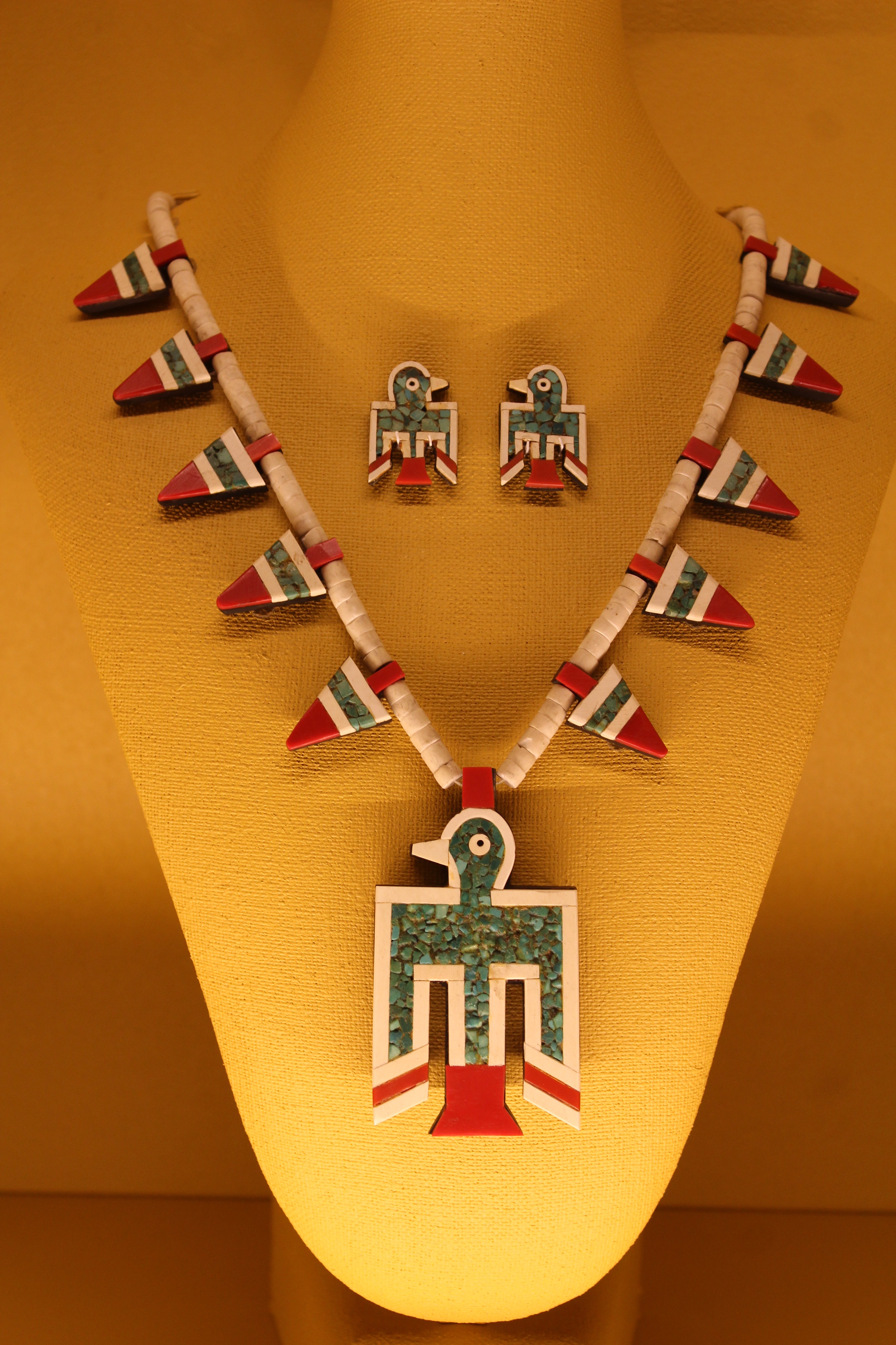 An example of a thunderbird necklace and matching earrings, made of plastic, turquoise and gypsum beads.