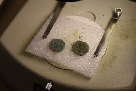 Two Irish pennies recently discovered by the archaeologists sit on a tray beneath a microscope in the Jamestown Rediscovery Project's lab. (Gregory Connolly/WYDaily)