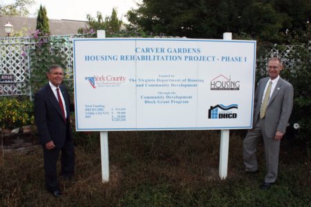 From left, Walter C. Zaremba, York County District 1 Board of Supervisor member and County Administrator Neil Morgan, stand with a sign recognizing contributions to the Carver Gardens housing rehabilitation project in September. (Courtesy of York County)