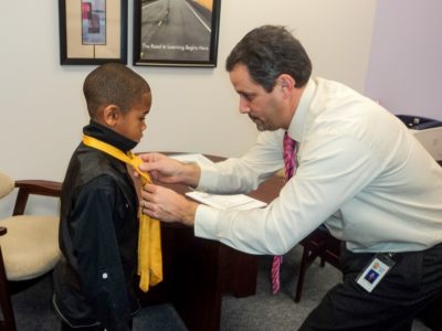 Bethel Manor Principal Mike Lombardo helps a student, Quentin Royster, adjust his tie on "Tie and Tiara Tuesday." (YCSD)