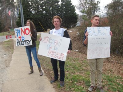 From left, Summer Chambers, Vincent Roselli and Jakob Weiss hold signs on Longhill Road while the presidential primary polling takes place at Lafayette High School. (Kirsten Petersen/ WYDaily)