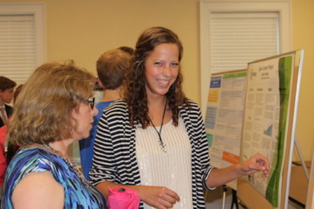 During an annual poster session at Christopher Newport University in Newport News, Warhill High School alumna Brook Byrd presents her research in the monitoring and calibration of a drift chamber as well as 3-D visualization of particle simulations at Jefferson Lab. (Photo courtesy Bob Byrd)
