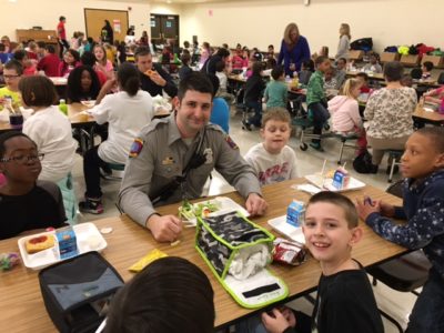 A York County Fire & Life Safety member eats lunch with children at Magruder Elementary School. (Courtesy York County School Division)