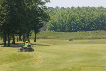 Lawn mowers cut the rough grass at the edge of the fairways. The mechanics of a golf course are designed to be out of sight and out of mind. (Steve Roberts, Jr./WYDaily)