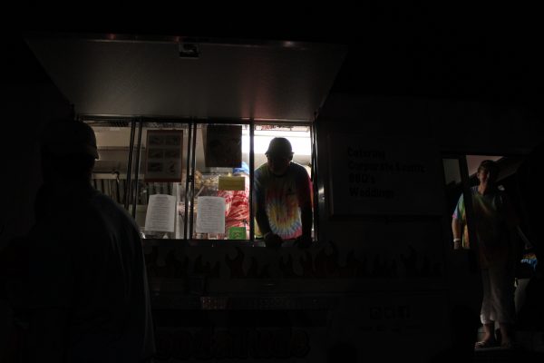 A man working in the Foodatude truck at Funhouse Fest waits at the window for customers to place their orders. (Sarah Fearing/WYDaily)