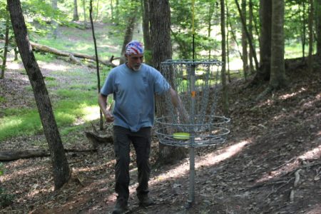 John Roy retrieves a disc from a disc golf basket at Waller Mill Park June 29. Colonial Disc Golf Club President John Roy is part of a growing group of disc golf lovers populating the Peninsula. (Sarah Fearing/WYDaily)