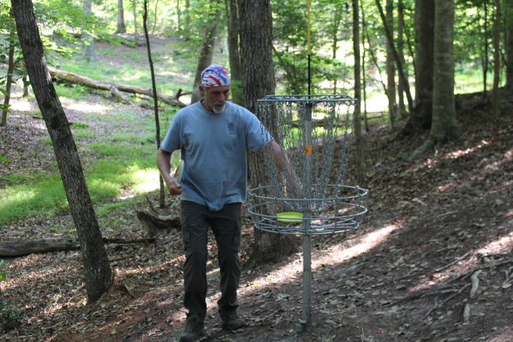 John Roy retrieves a disc from a disc golf basket at Waller Mill Park June 29. Colonial Disc Golf Club President John Roy is also of a growing group of disc golf lovers populating the Peninsula. (Sarah Fearing/WYDaily)