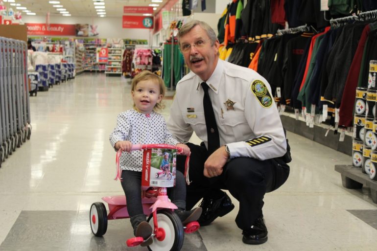 Sheriff J.D. Diggs poses with 18-month-old Cordelia Mcguire after she won a tricycle in a raffle during the 15th annual Shop with a Sheriff in 2016.. (Andrew Harris/WYDaily)
