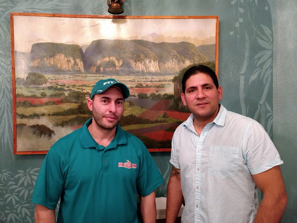 Alex Menendez (left) and Jose Lorenzo are co-owners of Habana Hemingway Cafe. Here they stand in front of one of Lorenzo's many paintings in Habana Hemingway Cafe. (Andrew Harris/WYDaily)