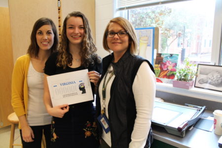 Jamestown High School junior Abigail Polansky has been named one of the state's eight finalists in a DMV license plate design competition. Here, Polansky poses for a photo with her design, Instructional Technology Research Teacher Amanda Morris (left) and art teacher Missy Furr. (Sarah Fearing/WYDaily)