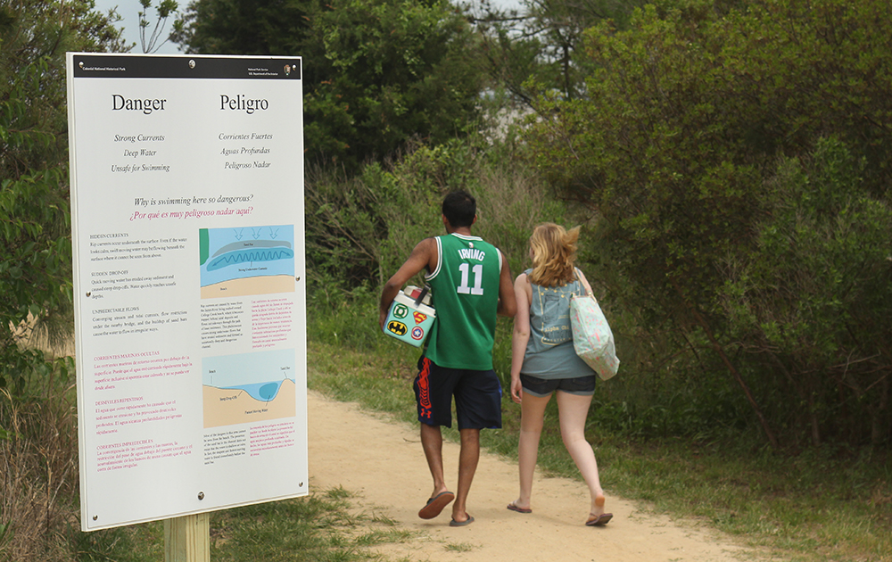 Visitors head to College Creek beach Saturday, May 5, 2018, one day after a Navy sailor drowned there. A sign at the head of the path to the College Creek beach warns visitors about the dangerous currents in the area. (Bryaan DeVasher/WYDaily)
