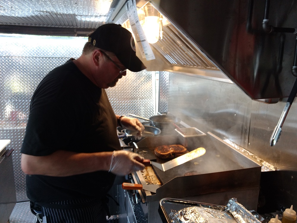 Scott Coelln prepares a meal in his mobile kitchen. (Andrew Harris/WYDaily)