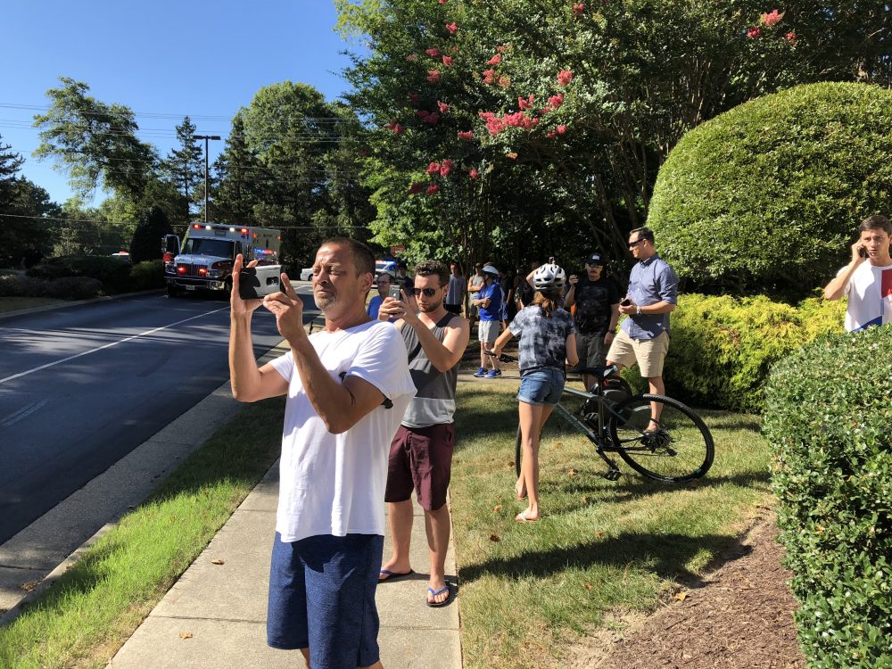 Onlookers take photographs and shoot video as firefighters battle a blaze Sunday, July 8, 2018, at the Bristol Commons apartment complex in Williamsburg. Witnesses said the fire was caused after a helicopter crashed and exploded. (WYDaily/Bryan DeVasher)