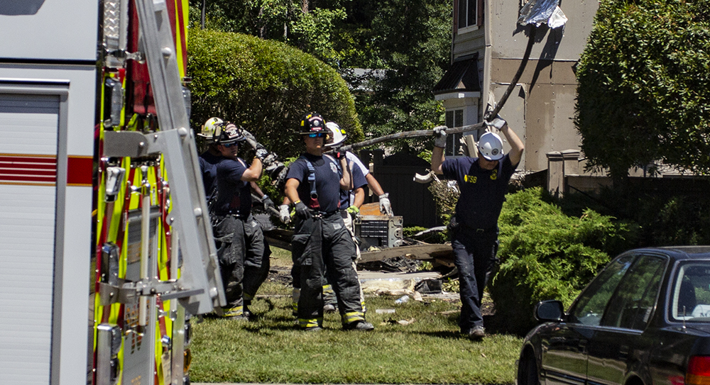 Firefighters and investigators remove debris from the site of a helicopter crash Monday, July 9, 2018, at the Bristol Commons townhouse complex. (WYDaily/Bryan DeVasher)