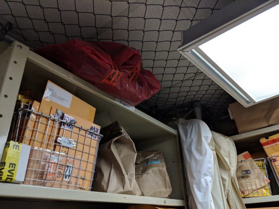 A red biohazard bag containing the bloody clothing of a car crash victim overlooks the Williamsburg Police property and evidence room from a top shelf. (WYDaily/Sarah Fearing)