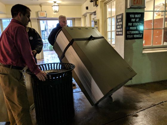 A city staff member removes the old pay station from the Prince George Parking Garage on Thursday. The City of Williamsburg is switching to a gateless, license plate-based system at the parking garage. (WYDaily/Sarah Fearing)