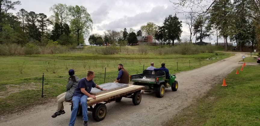 Archaeologists transport the Knight's Tombstone to the Memorial Church, which can be seen in the distance. (WYDaily/Courtesy of Jamestown Rediscovery (Preservation Virginia))