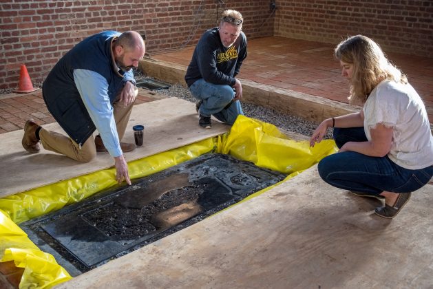 Director of Collections and Conservation Michael Lavin, Senior Conservator Dan Gamble and Associate Curator Leah Stricker examine the Knight's Tombstone after it successfully settled into its final (and former) home in the Memorial Church. (WYDaily/Courtesy of Jamestown Rediscovery (Preservation Virginia))