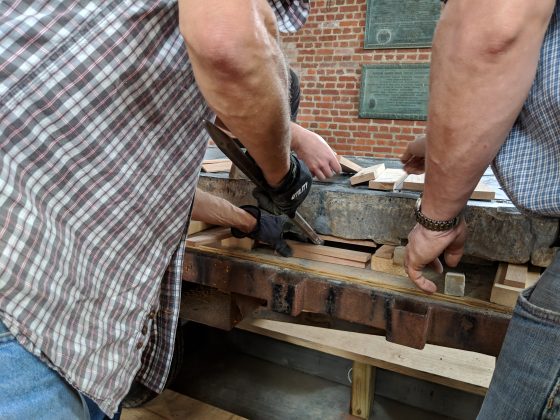 Jonathan Appell uses a piece of wood and a crowbar to slowly lift the Knight's Tombstone. (WYDaily/Sarah Fearing)