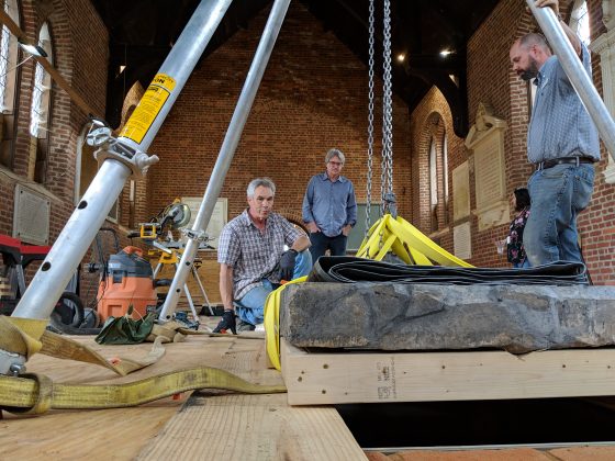 Jamestown Rediscovery and Jonathan Appell from Atlas Preservation used a tripod hoist to lift the Knight's Tombstone off a transportation cart and into a permanent setting in the floor of the Memorial Church Tuesday. (WYDaily/Sarah Fearing)