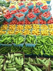 Colorful rows of organic produce, tomatoes, peppers, and okra, lines Amy's Garden stall at the WIlliamsburg Farmers Market. (WYDaily/Courtesy of Amy Hicks)