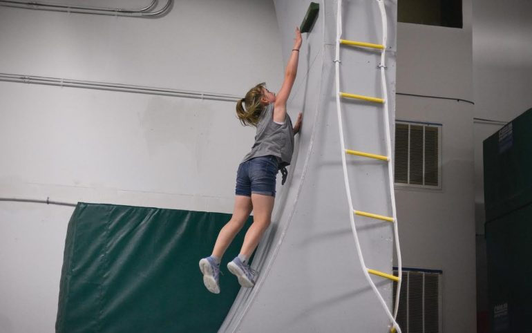 Hannah Rothwell reaches for the top while testing her strength on the Chain Breakers Warrior Academy obstacle course. (WYDaily/Courtesy of Mary Rothwell Photography)