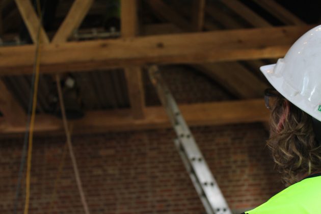 Ben Sunderlin observes a bell he made as it is hoisted into the belfry of a timber frame church exhibit at Jamestown Tuesday July 16, 2019. (WYDaily/Sarah Fearing)