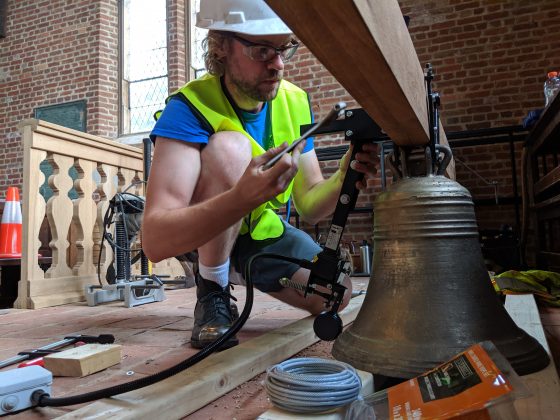 Ben Sunderlin checks out a bell he made before it was hoisted into the belfry of a timber frame church exhibit at Jamestown Tuesday July 16, 2019. (WYDaily/Sarah Fearing)
