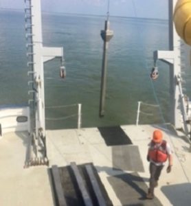 Taylor Moore, mate aboard the R/V Virginia, assists in deployment of a sediment core to test for chlordecone breakdown products in the James River. (John Olney Jr./VIMS/Southside Daily)