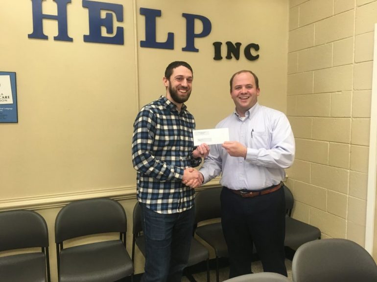 Scott Rutter, executive pastor at Next Level Church, gives a check for more than $4,000 to HELP's A Night's Welcome. (WYDaily/Courtesy HELP)