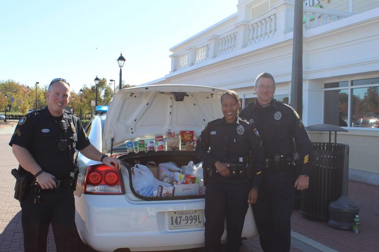 James City County Police officers stand with a police cruiser trunk packed with donated goods.(WYDaily/Courtesy of James City County Police)