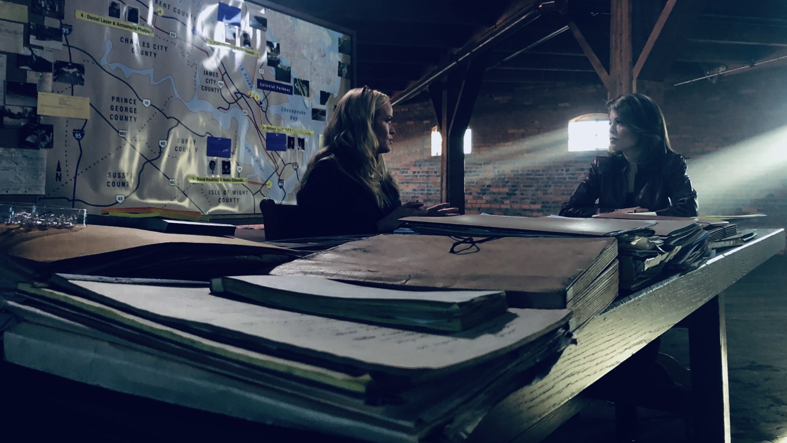 Former FBI Special Agent Maureen O’Connell, left, and former criminal prosecutor Loni Coombs, right, sit in front of a map of the Historic Triangle, discussing the Colonial Parkway murders. (WYDaily/ Courtesy of the Oxygen Network Publicity team)